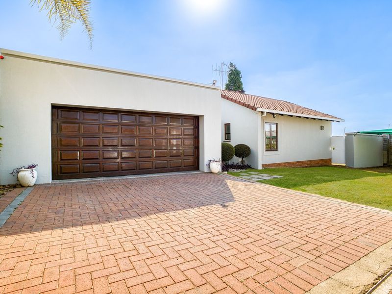 Front view of the property featuring a paved driveway, double garage, and well-maintained lawn area.