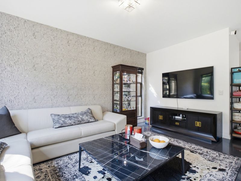 A well-maintained living room featuring a textured accent wall, tiled flooring, and modern recessed ceiling lighting.