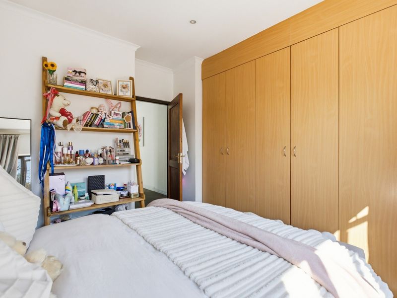 A well-maintained bedroom featuring extensive built-in wooden cupboards and recessed ceiling lighting, providing ample storage and a clean, functional living space.