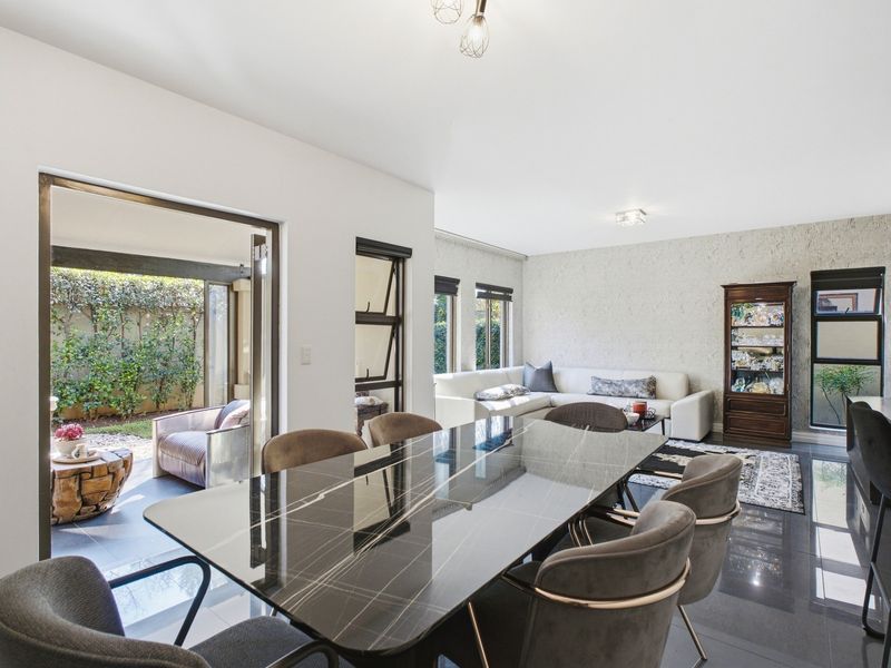 Spacious open-plan living and dining area featuring sleek tiled floors, a textured feature wall, and large sliding doors leading to an outdoor patio.