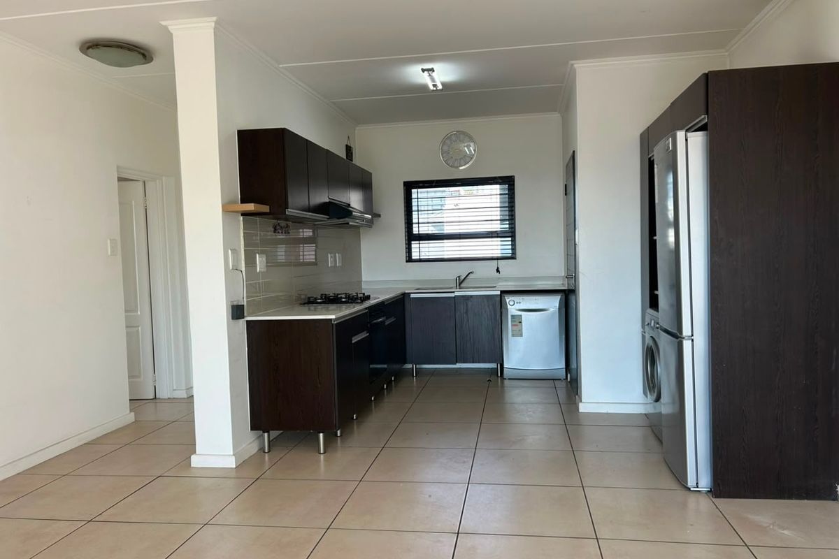 A functional kitchen featuring dark wood cabinetry, tiled flooring, a gas hob, and integrated appliances, offering a clean and practical workspace.