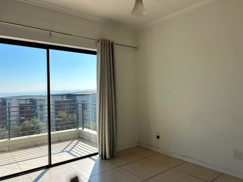 An empty bedroom featuring tiled floors, a sliding glass door leading to a balcony, and neutral wall finishes.
