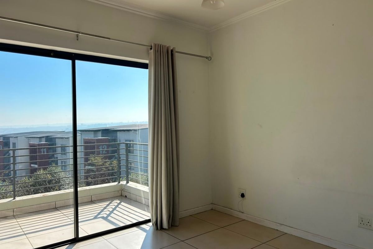 An empty bedroom featuring tiled floors, a sliding glass door leading to a balcony, and neutral wall finishes.