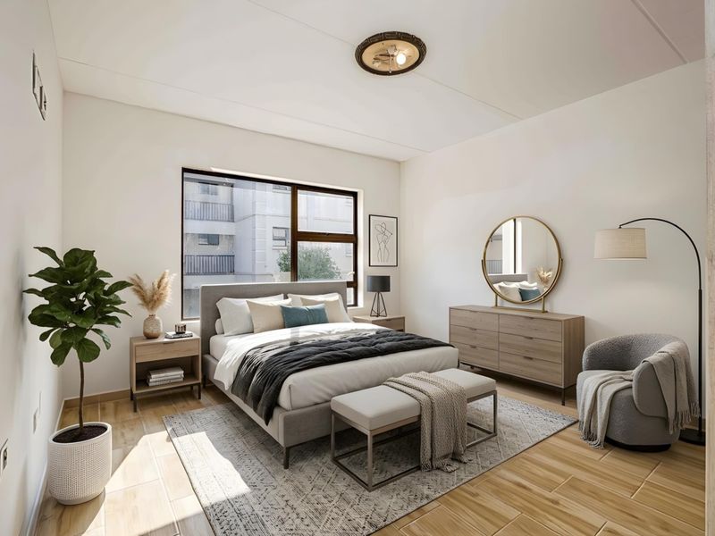 A well-lit, modern bedroom featuring wood-look tile flooring, a large window, and a neutral color palette.