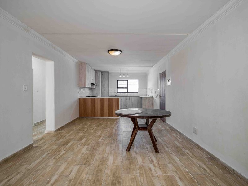 Open-plan living and kitchen area featuring wood-look tile flooring, modern cabinetry, and a functional kitchen island layout.