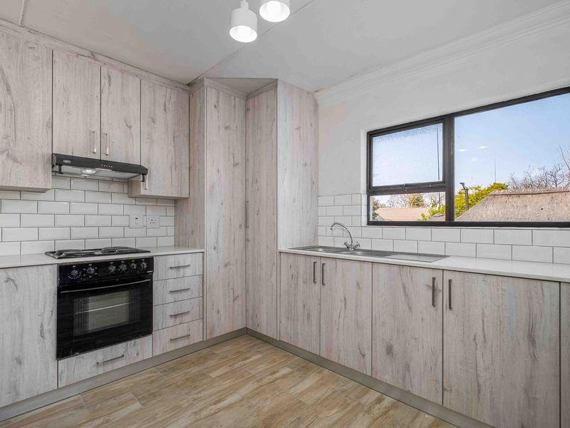 Modern kitchen featuring light wood-grain cabinetry, quartz countertops, subway tile backsplash, and integrated stainless steel appliances.