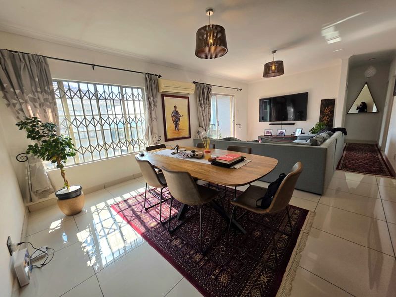 Spacious open-plan living and dining area featuring tiled floors, a split-system air conditioner, and large windows with security gates for added peace of mind.