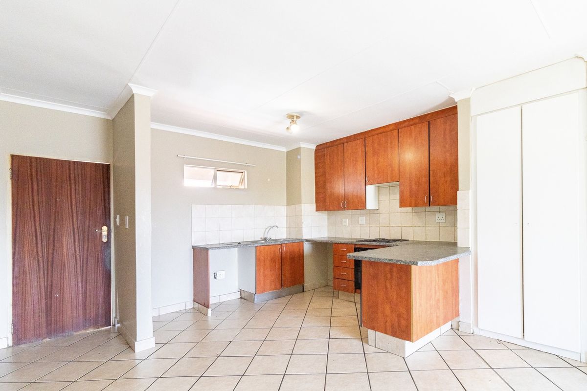 A functional kitchen featuring laminate cabinetry, stone-look countertops, tiled backsplash, and ceramic flooring, offering a clean and practical layout.