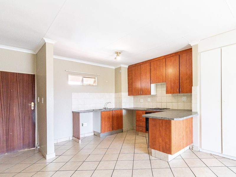 A functional kitchen featuring laminate cabinetry, stone-look countertops, tiled backsplash, and ceramic flooring, offering a clean and practical layout.