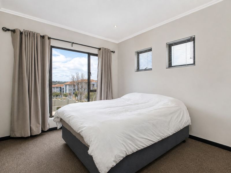A well-maintained bedroom featuring neutral walls, carpet flooring, and a large sliding glass door providing natural light and access to the exterior.