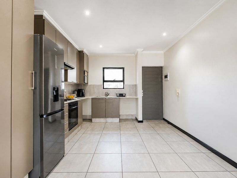 A modern, well-maintained kitchen featuring neutral cabinetry, tiled flooring, integrated appliances, and recessed lighting, offering a clean and functional workspace.