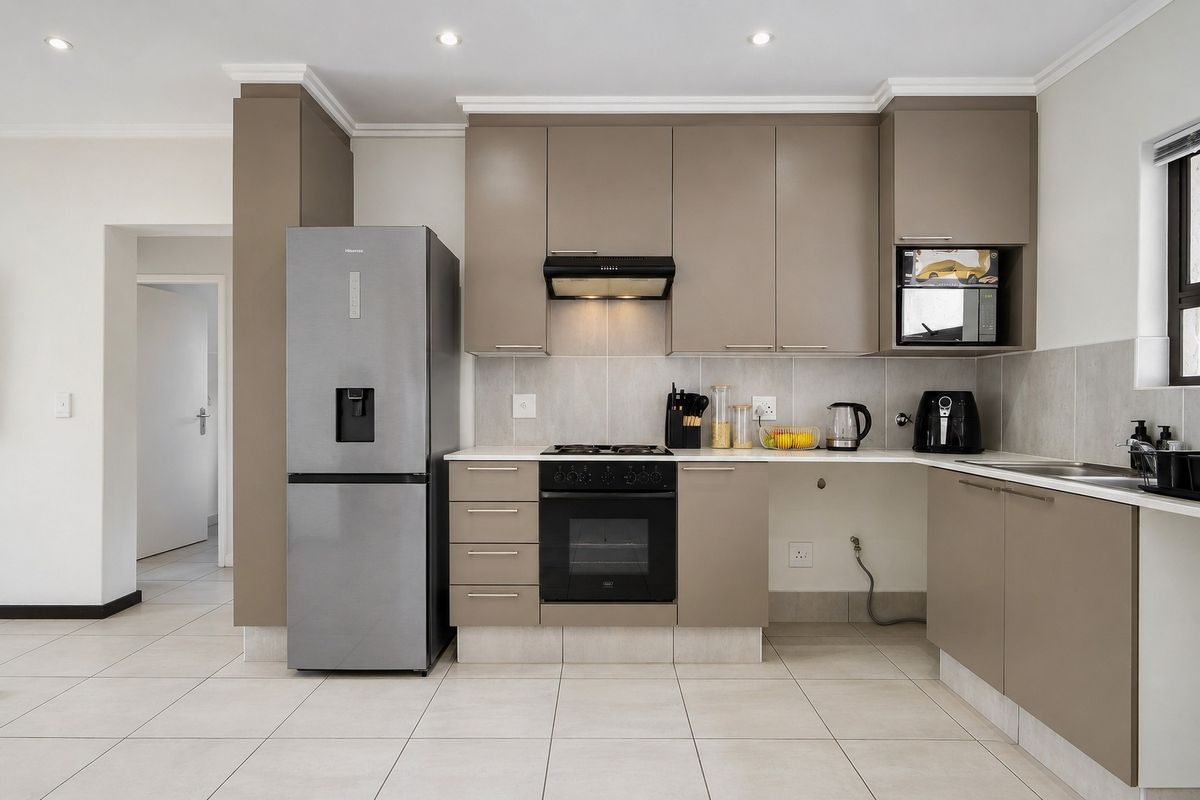 Modern kitchen featuring sleek taupe cabinetry, stone countertops, integrated appliances, and tiled flooring, offering a clean and functional culinary space.