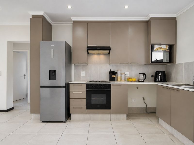 Modern kitchen featuring sleek taupe cabinetry, stone countertops, integrated appliances, and tiled flooring, offering a clean and functional culinary space.