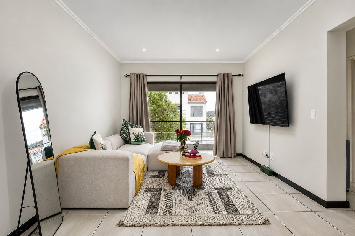 A bright and modern living room featuring tiled flooring, recessed lighting, and a sliding glass door leading to a balcony.