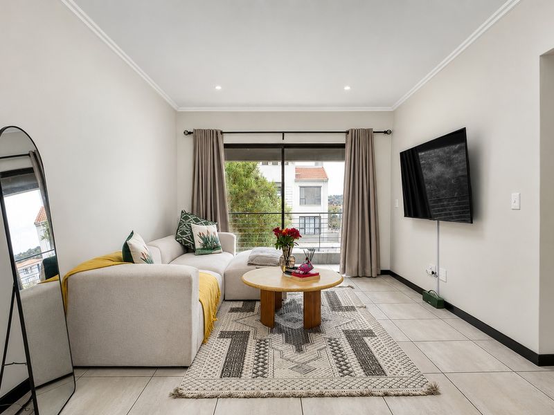 A bright and modern living room featuring tiled flooring, recessed lighting, and a sliding glass door leading to a balcony.