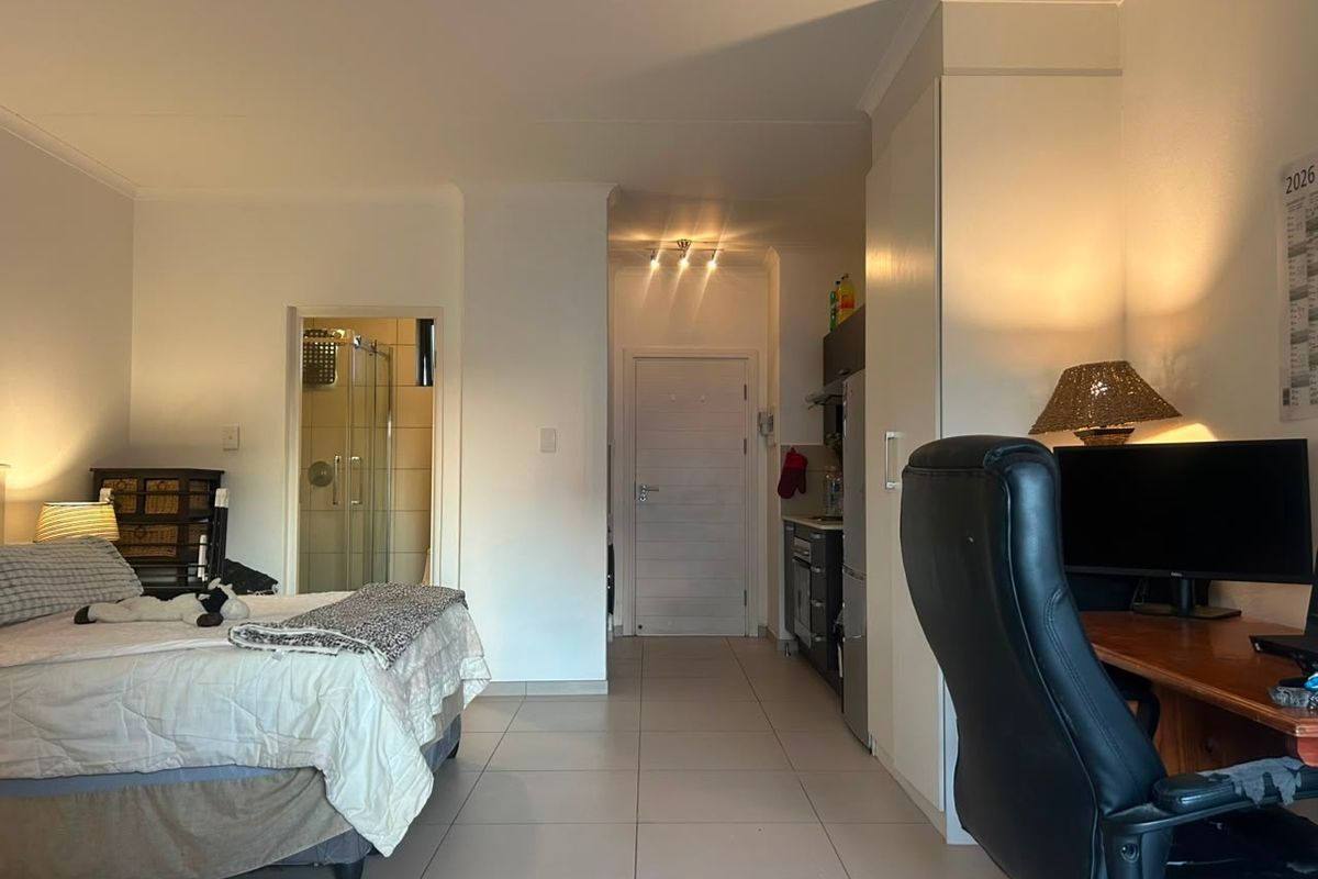Open-plan studio apartment featuring tiled flooring, built-in storage, and an integrated bathroom with a shower enclosure.