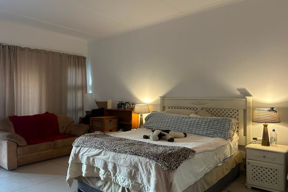 A spacious bedroom featuring tiled flooring and neutral wall finishes, offering a comfortable layout with natural light through the window.