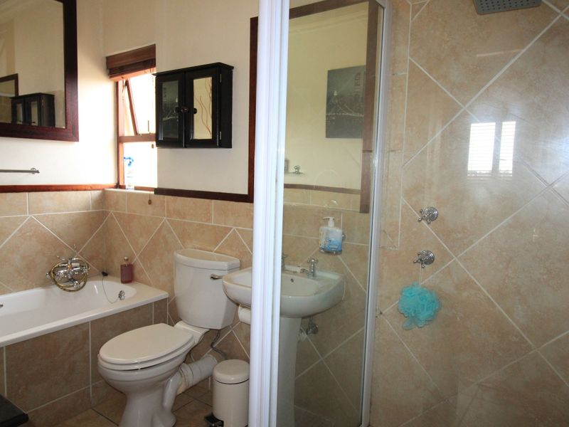 A functional bathroom featuring a bathtub, pedestal sink, and a separate shower enclosure with tiled walls and flooring.