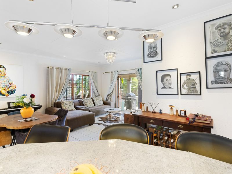 Spacious open-plan living and dining area featuring tiled flooring, recessed lighting, and direct access to an outdoor patio through sliding glass doors.