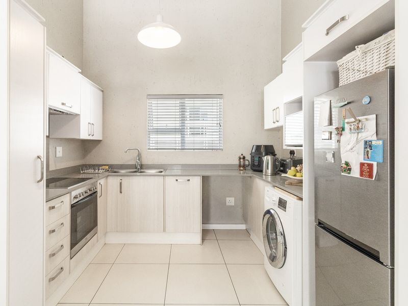 A modern, well-maintained kitchen featuring light-toned cabinetry, integrated appliances, tiled flooring, and a functional layout with ample counter space.