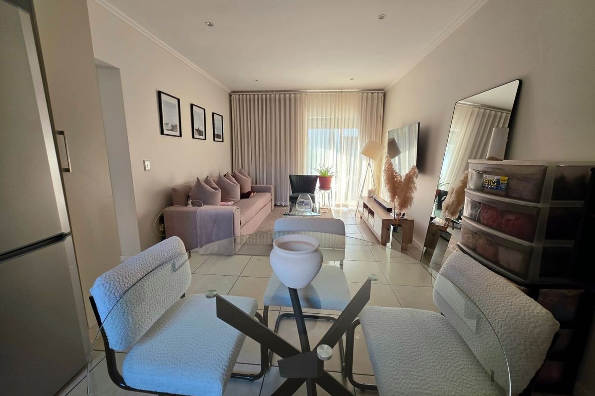 An open-plan living and dining area featuring neutral tiled flooring, recessed lighting, and large sliding glass doors leading to an outdoor space.