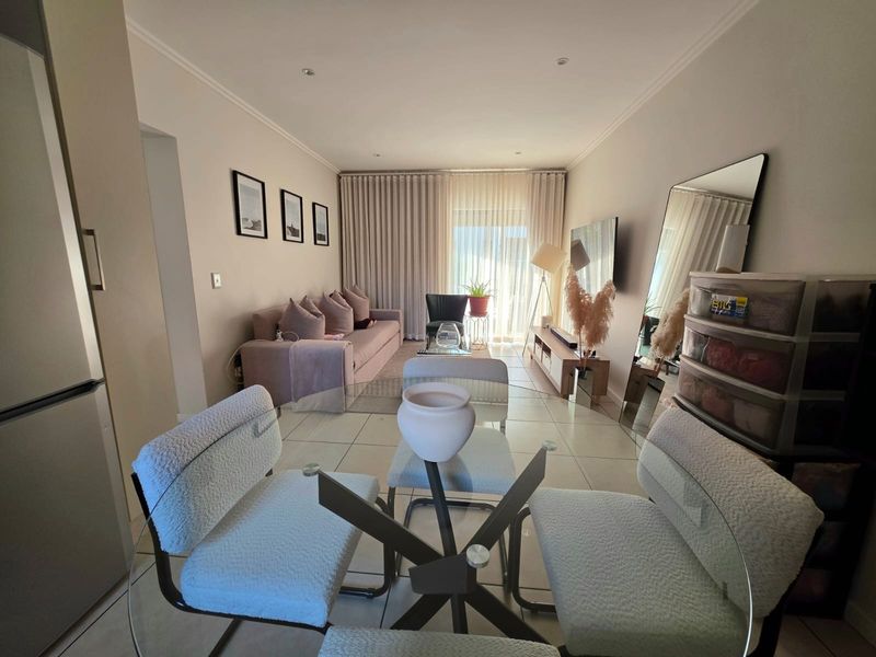 An open-plan living and dining area featuring neutral tiled flooring, recessed lighting, and large sliding glass doors leading to an outdoor space.