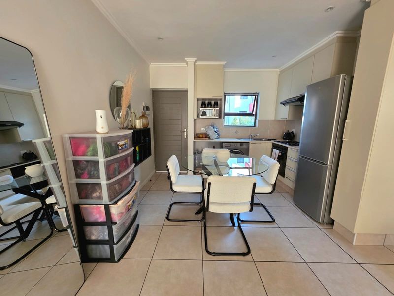 Open-plan kitchen and dining area featuring tiled flooring, built-in cabinetry, and integrated appliances, providing a functional and compact living space.