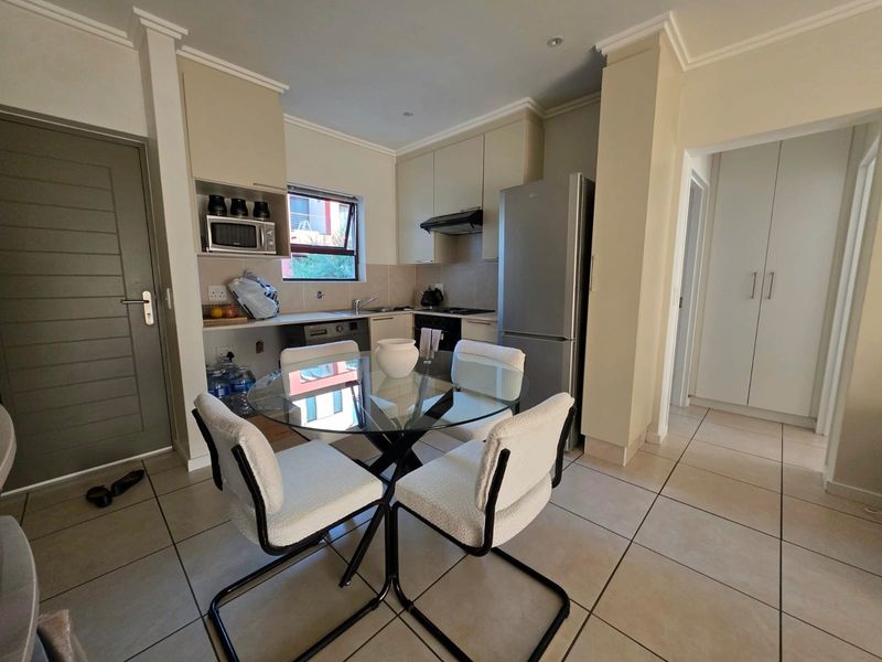 Open-plan kitchen and dining area featuring tiled flooring, neutral cabinetry, and built-in kitchen fixtures, providing a functional and well-lit living space.