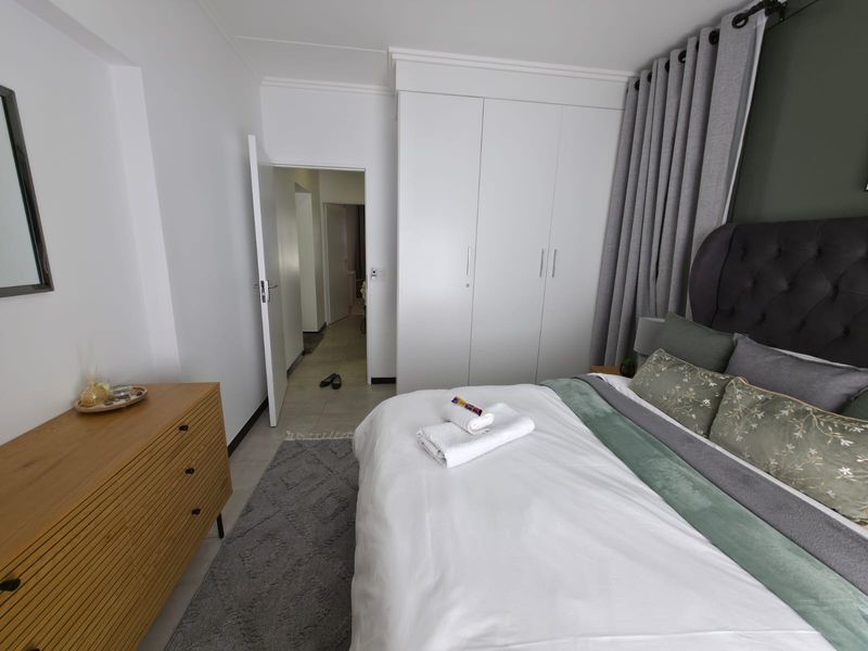 A well-maintained bedroom featuring built-in wardrobes, neutral tiled flooring, and clean finishes, offering a comfortable and functional living space.