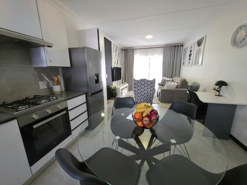 Modern open-plan living area featuring a compact kitchen with gas hob, built-in oven, and seamless flow to the lounge and dining space.