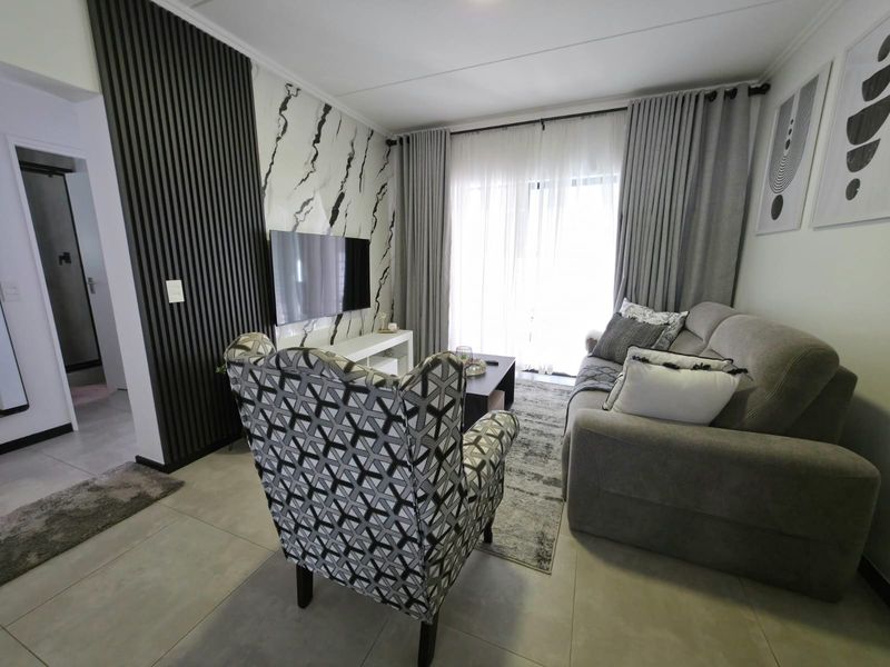 Modern living room featuring a stylish slatted timber accent wall, marble-look wall cladding, tiled flooring, and direct access to a balcony through sliding doors.