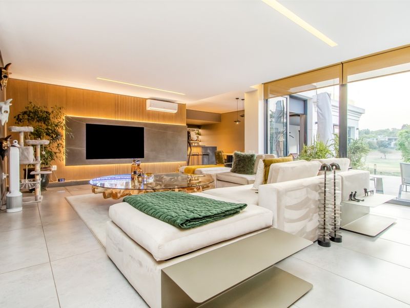 Modern open-plan living area featuring a stone feature wall, recessed lighting, large format floor tiles, and seamless access to an outdoor patio.