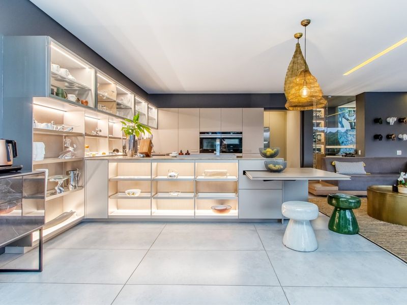 Modern open-plan kitchen featuring sleek built-in cabinetry, integrated appliances, and ambient under-cabinet lighting, seamlessly flowing into the adjacent living area.