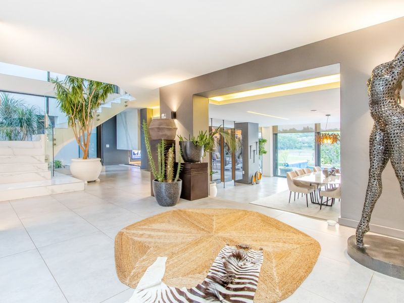 Spacious open-plan living area featuring high-end finishes, a grand marble staircase with glass balustrade, and seamless flow to the dining and outdoor spaces.