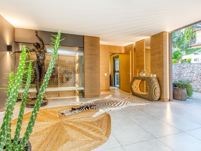 Modern living area featuring high-end wood paneling, integrated wine cellar, recessed lighting, and large sliding glass doors opening to an outdoor space.