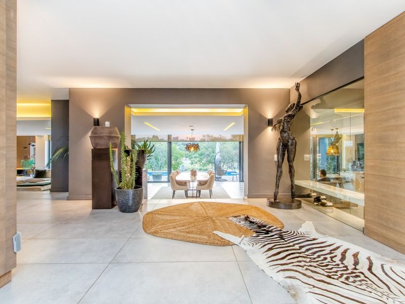 Spacious open-plan living area featuring large format floor tiles, recessed lighting, and a modern glass partition, creating a seamless flow between interior spaces.