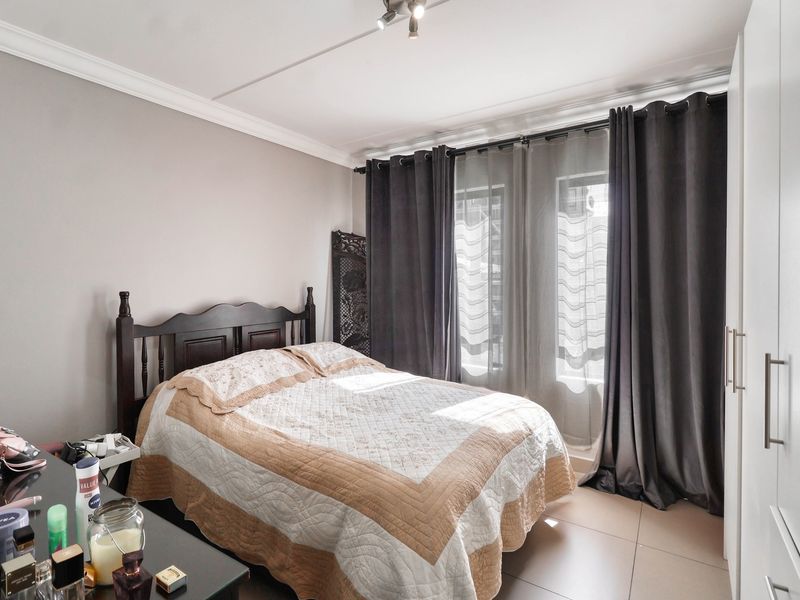 A well-maintained bedroom featuring tiled flooring, built-in wardrobe storage, and ceiling cornice detailing, offering a clean and functional living space.