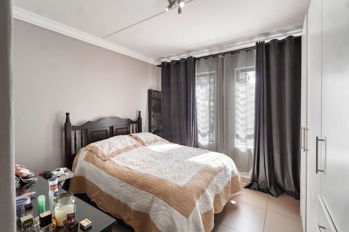 A well-maintained bedroom featuring tiled flooring, built-in wardrobe storage, and ceiling cornice detailing, offering a clean and functional living space.