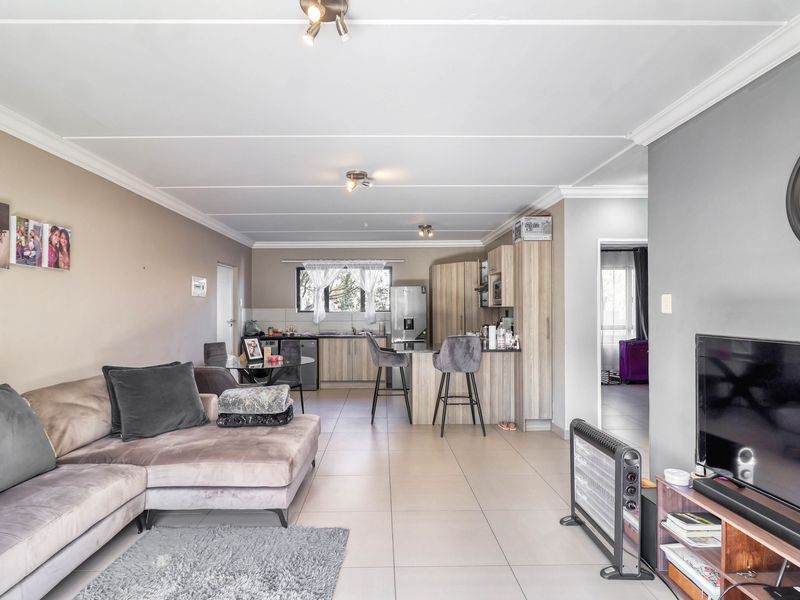 Open-plan living area featuring a modern kitchen with island, tiled flooring, and neutral wall finishes, creating a functional and connected living space.