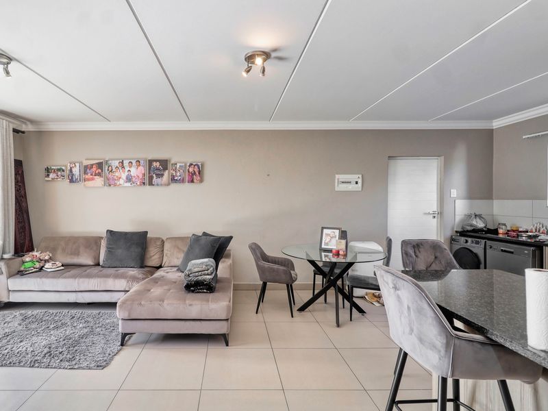 An open-plan living and kitchen area featuring tiled floors, modern cabinetry with granite countertops, and integrated kitchen appliances.