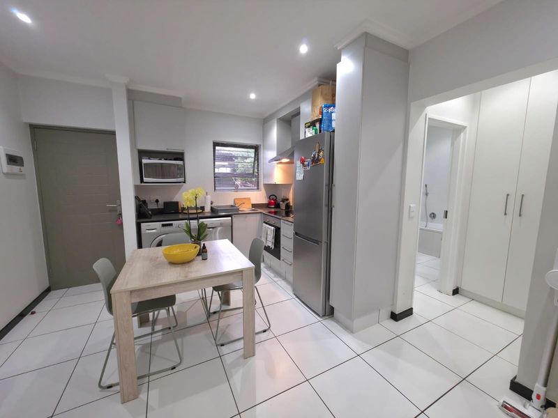Modern open-plan kitchen featuring sleek cabinetry, built-in appliances, and tiled flooring, seamlessly connected to the living area and adjacent hallway.