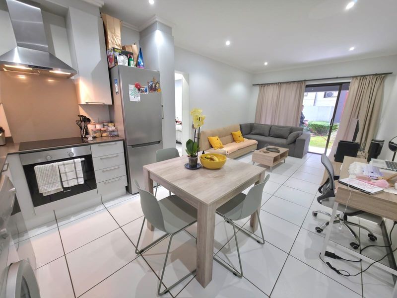 Modern open-plan living area featuring a well-equipped kitchen with built-in appliances, tiled floors, and direct access to an outdoor patio space.