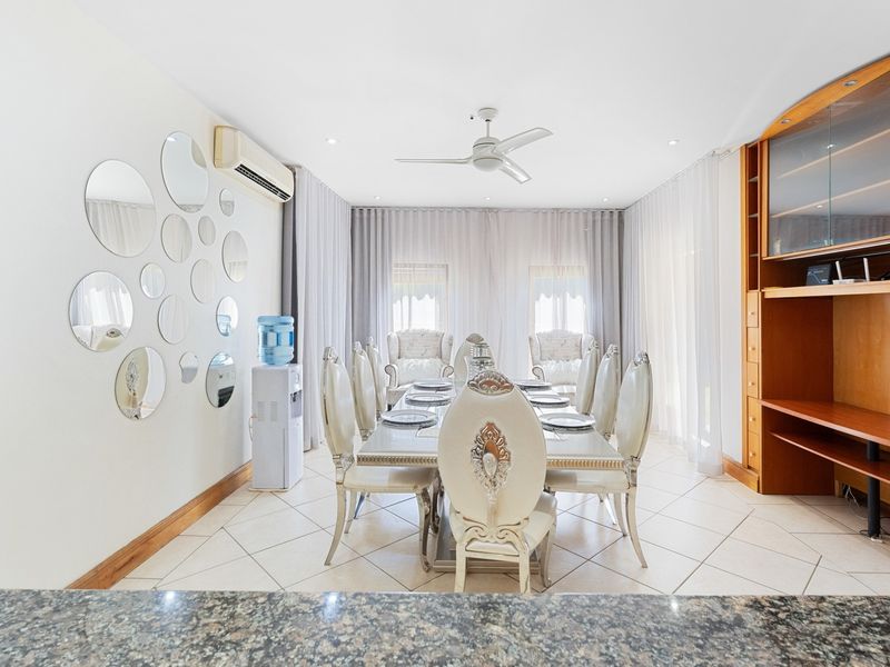 A well-lit dining room featuring tiled flooring, a ceiling fan, split-system air conditioning, and built-in wooden cabinetry.