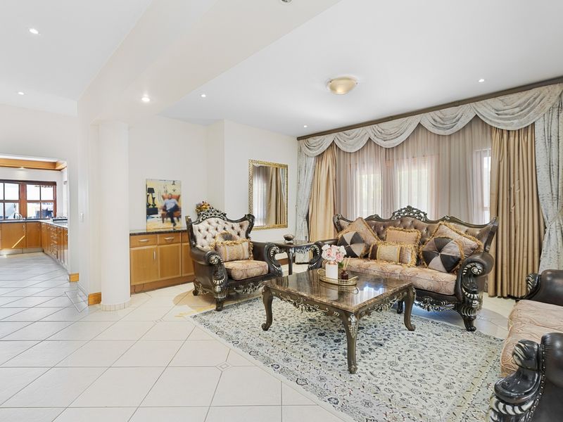 Spacious open-plan living area featuring tiled flooring, recessed lighting, and a seamless transition to the adjacent kitchen with built-in cabinetry.