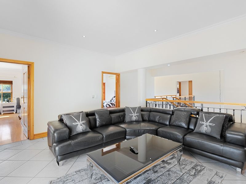 A spacious living area featuring tiled floors, recessed lighting, and a decorative wrought iron balustrade overlooking the lower level.