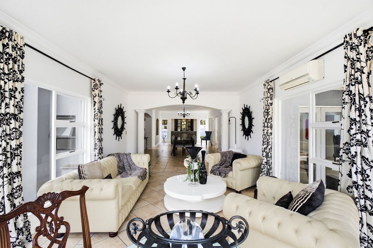 Spacious living room featuring tiled flooring, an arched entryway, decorative columns, and a split-system air conditioner, leading through to an adjacent dining area.