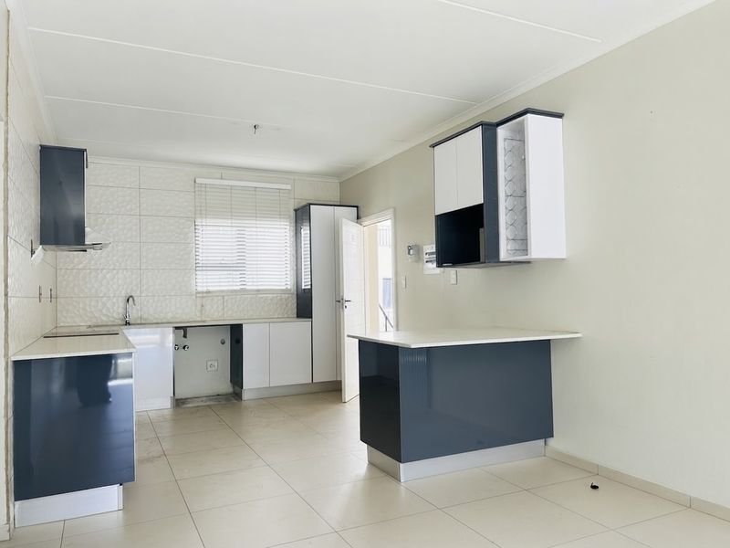 Modern kitchen featuring two-tone cabinetry, stone countertops, tiled backsplash, and ceramic flooring. The space is clean and ready for appliance installation.