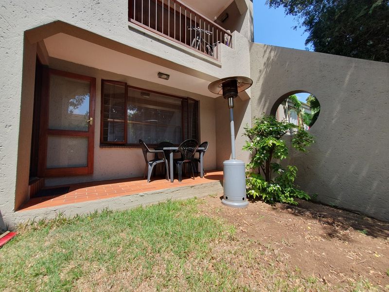 A ground-floor patio area featuring tiled flooring, a circular architectural wall detail, and access to a small private garden space.