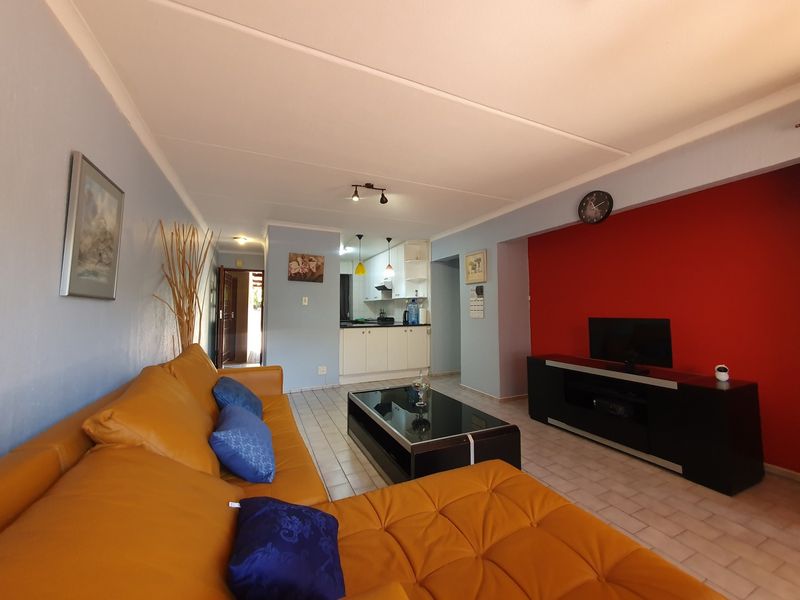 Open-plan living area featuring tiled flooring and a connected kitchen with built-in cabinetry, creating a functional and integrated living space.