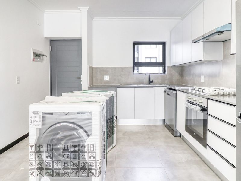 Modern kitchen featuring white cabinetry, stainless steel appliances, gas hob, extractor fan, and tiled flooring in a clean, contemporary layout.